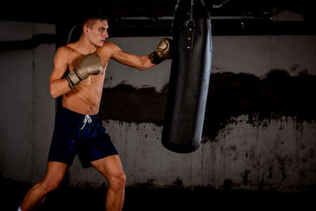 Concept of a healthy lifestyle.Young athlete fighter practicing kicks with punching bag.Kick boxer boxing as exercise for the fightの写真素材