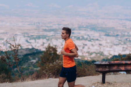 Athletic fit young sport fitness model in his twenties in full body length on road outside in mountainの写真素材