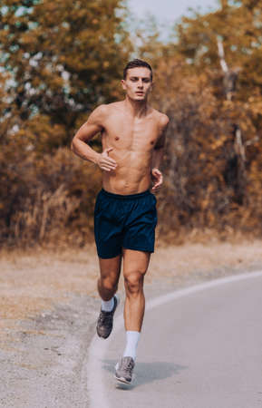 Man running sprinting on road in mountains. Fit male fitness runner during outdoor workout Young caucasian manの写真素材