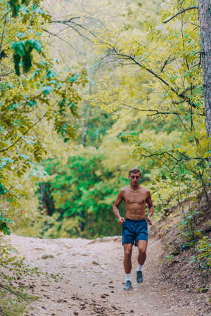 Fitness male sport fitness model sprinting outdoors on mountain pathの写真素材