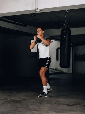 Muscular young man in boxing gloves and shorts shows the different movements and strikesの写真素材