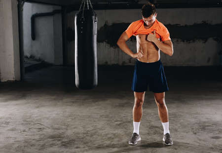 A handsome young sportsman change clothes after box training