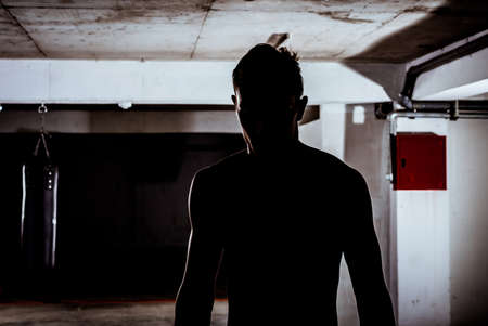 Silhouette of a strong fighter. Confident young fitness man with strong handsの写真素材