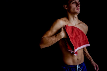 Young shirtless man wiping his body with a towelの写真素材