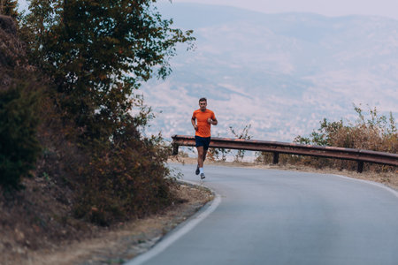 Man jogging s while sprinting on road in mountainsの写真素材