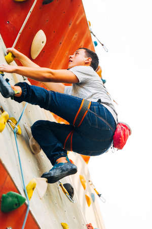 Young climber guy climbing on practical rock in climbing center, boulderingの写真素材