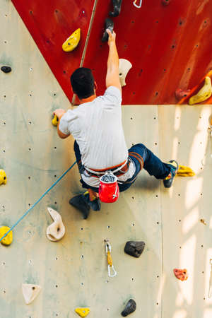 Young climber guy climbing on practical rock in climbing center, boulderingの写真素材
