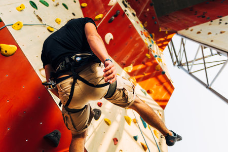 Young man descend down an outdoors artificial rock wallの写真素材