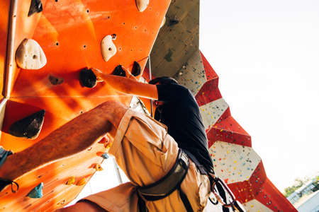 Young climber guy climbing on practical rock in climbing center, bouldering