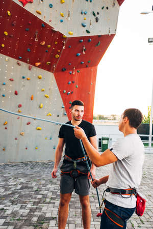 Young climber team prepare their safety harness belt for bouldering