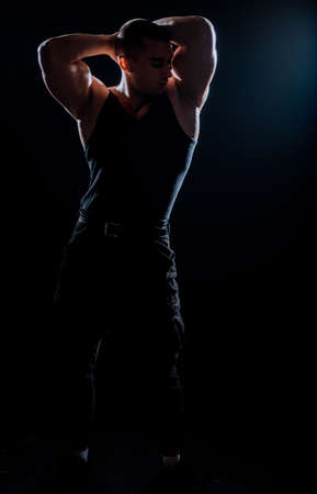 Bodybuilder posing. Beautiful sporty guy male power. Fitness muscled man in shirt on dark backgroundの写真素材