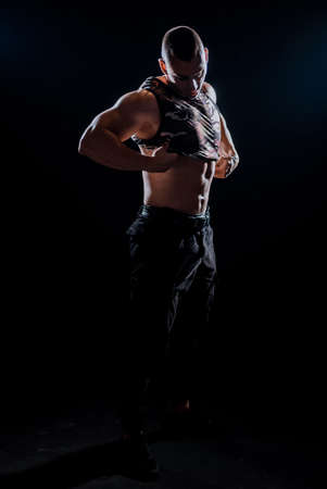 Sweaty sportsman taking off clothes as it is hot in the fitness clubの写真素材