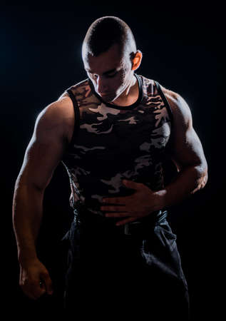 Muscular and fit young bodybuilder fitness male model posing over black backgroundの写真素材