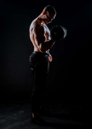 Muscular man working out in gym doing exercises with dumbbells, strong maleの写真素材