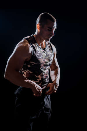 Close-up of a young athlete showing his sporty torso against a dark backgroundの写真素材