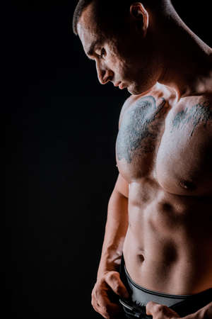 Portrait of young muscular man is flexing his muscles on dark backgroundの写真素材
