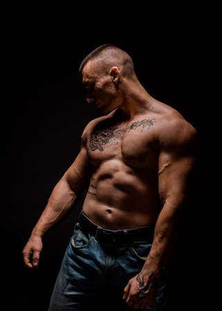 Portrait of young muscular man is flexing his muscles on dark backgroundの写真素材