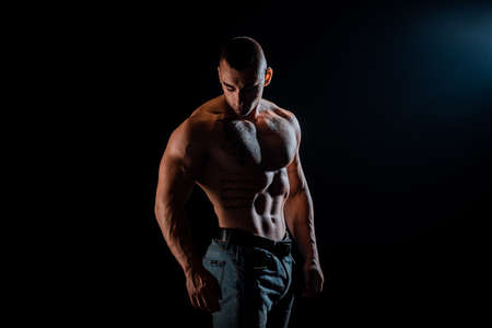 Close-up of a young athlete showing his sporty torso with a tattoos against a dark backgroundの写真素材