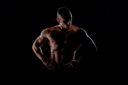 Muscular and fit bodybuilder fitness male model posing over black background