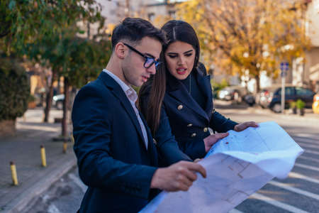 Business male and female architects looking at the blueprint about a building project outdoors.の写真素材