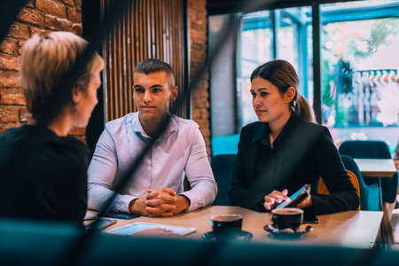 Lovely couple having meeting in the cafe with their business consultantの写真素材