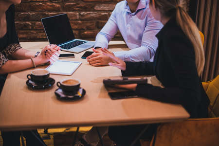 Image with focus on a table in a cafeteria with businesspeople, tablets, laptop and smartphonesの写真素材