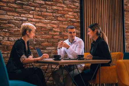 Happy businessman and businesswomen having teamwork meeting for developing new strategies in a cafe.
