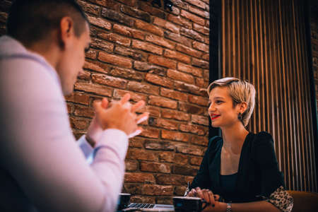 An attractive blonde with red lipstick explaining her strategy on a business meeting in a restaurantの写真素材