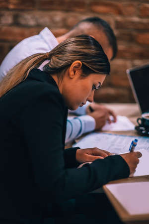 Young couple signing paper contract together at business meeting in a cafe barの写真素材