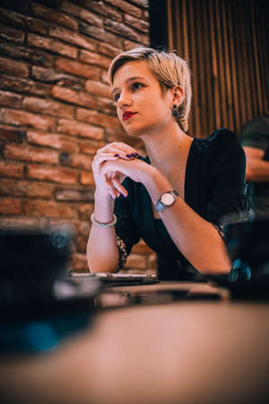 Image of a young attractive businesswoman with a cup of coffee working with her clients in a cafe bar.の写真素材