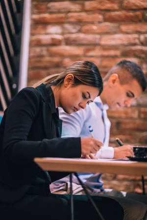 Young couple signing paper contract together at business meeting in a cafe bar
