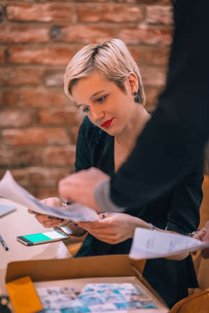 Image of a young attractive businesswoman with a cup of coffee working with her clients in a cafe bar.の写真素材