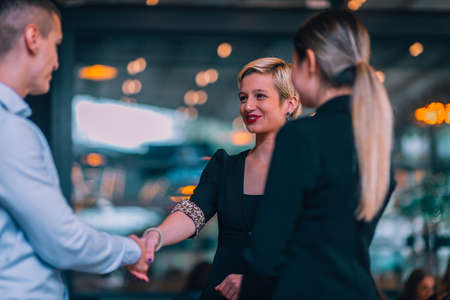 Image of a young attractive businesswoman shaking hands with her client for a deal in front of the office.の写真素材