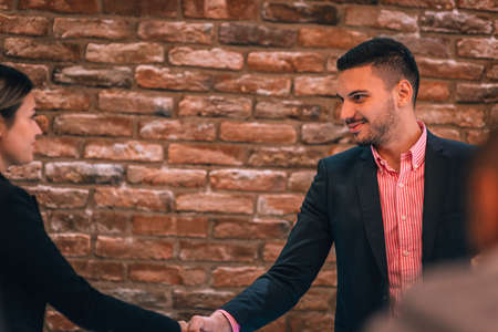 Image of a young handsome businessman shaking hands with his client  inside a cafe bar.の写真素材