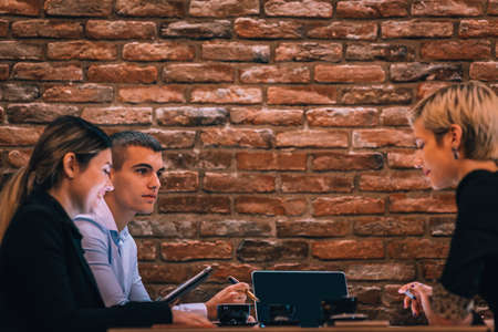 Group of three people with their laptop and tablet working on a project in a cafe.の写真素材
