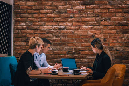 Group of three people with their laptop and tablet working on a project in a cafe.の写真素材