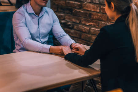 Close up of a beautiful young couple holding hands while sitting in a cafeの写真素材