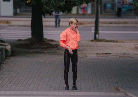 Close up portrait of young fitness blonde woman in sportswear listening music with headphones after training outdoorsの写真素材