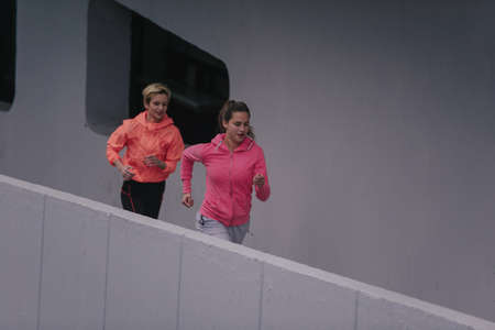 Two attractive female athletes preparing for a run in an urban environment