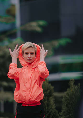 Portrait of a pretty fitness girl in earphones doing stretching exercises at the park