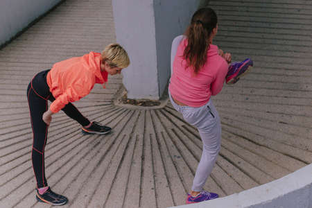Athletic fit female runners stretching in an urban environmentの写真素材