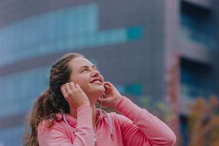 Portrait of a smiling fitness girl listening to music outdoorsの写真素材