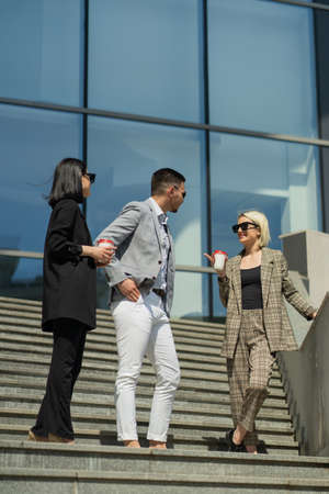 Three well dressed business people are talking on their breakの写真素材