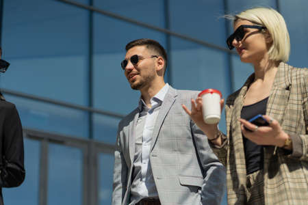 Three urban business people are talking about the business while drinking coffeeの写真素材