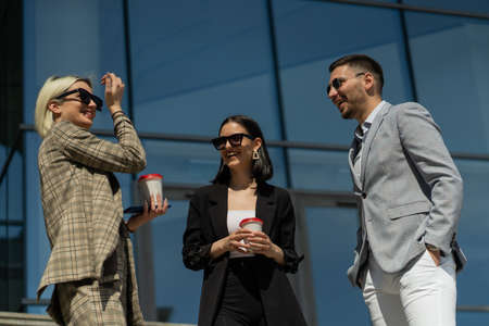Three urban business people are talking and smiling on their break