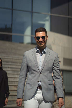 Urban well suited businessman is walking and smilingの写真素材
