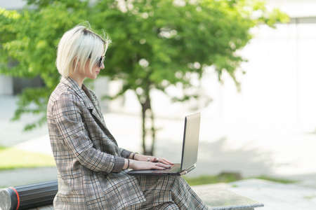 Businesswoman is making and sending mail to her partners on her laptop, outsideの写真素材