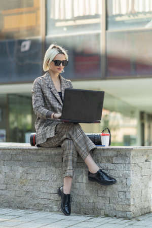 Urban businesswoman is working on her laptopの写真素材