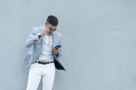 Handsome and attractive businessman is thinking about the offer he recived on his phoneの写真素材