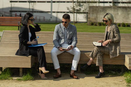 Three urban business people are sitting and discussing the plans for the companyの写真素材